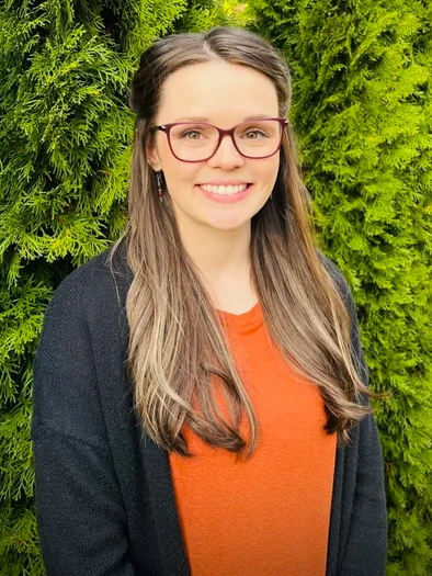 Heather smiling in front of green trees